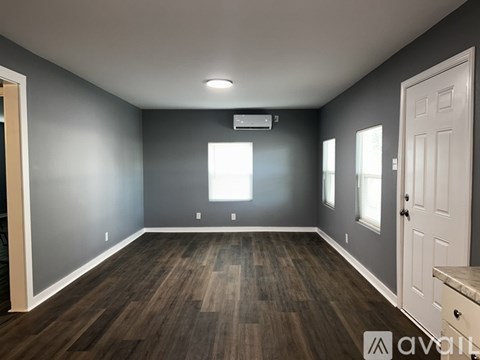 A spacious room with wooden flooring and a white door.