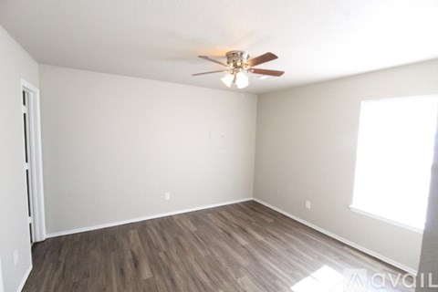 A room with a ceiling fan and wooden flooring.