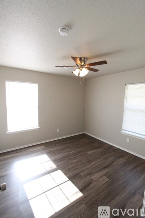A room with a ceiling fan and two windows.