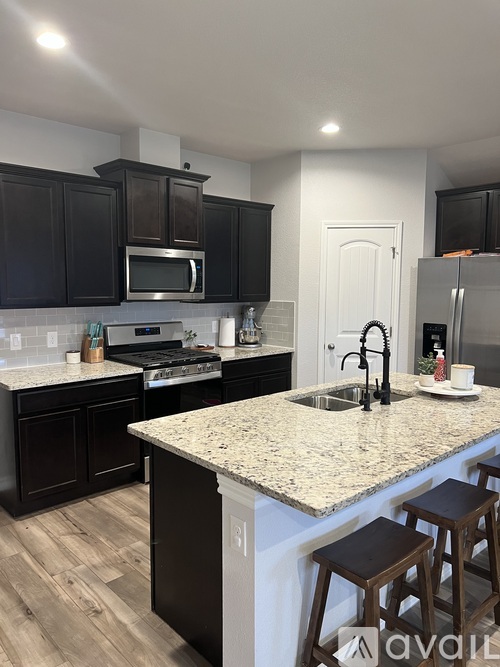 A kitchen with dark brown cabinets and a granite countertop.