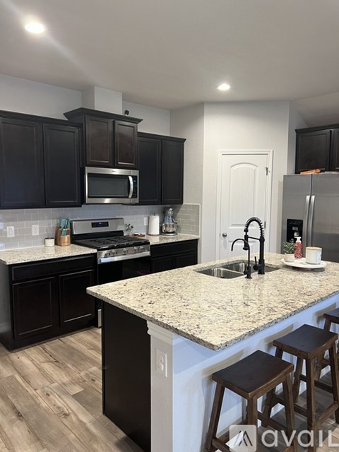 A kitchen with dark brown cabinets and a granite countertop.