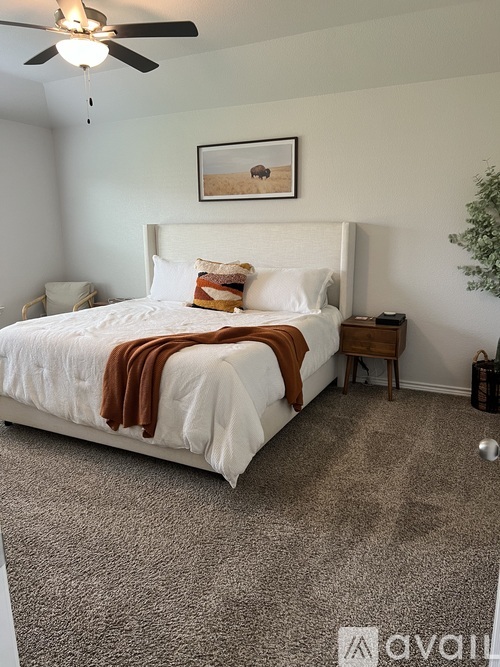 A bedroom with a large bed and a ceiling fan.