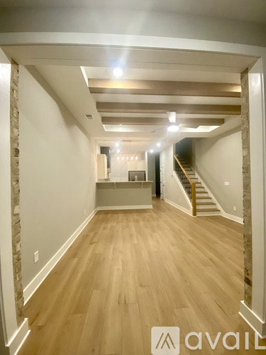 A spacious room with wooden floors and a staircase.