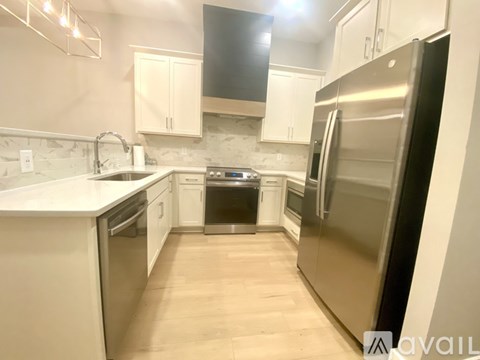 A kitchen with a black refrigerator, white cabinets, and a stove top oven.