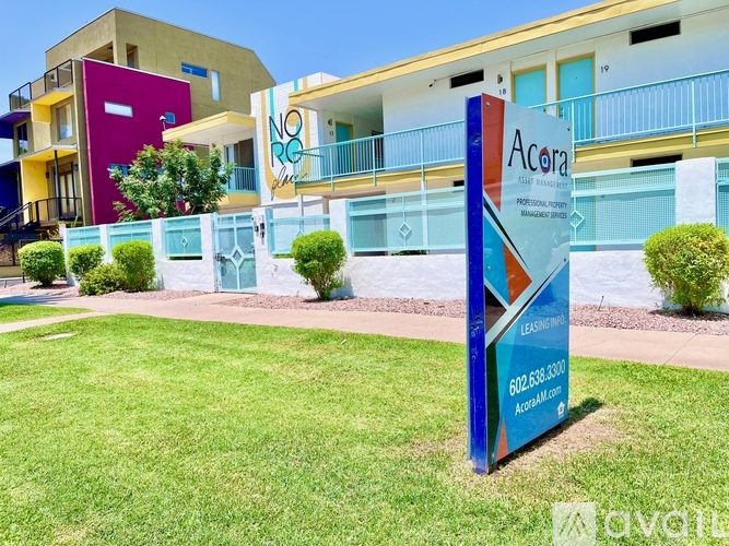 A colorful sign for Acora apartments stands in front of the building.