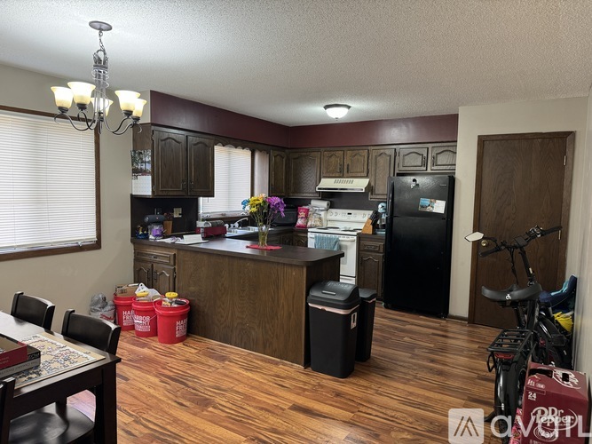 A kitchen with wooden floors and a black refrigerator.