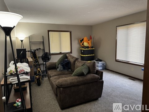 A living room with a brown couch and a lamp.