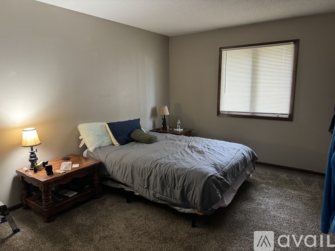 A bedroom with a bed, nightstand, and lamp.