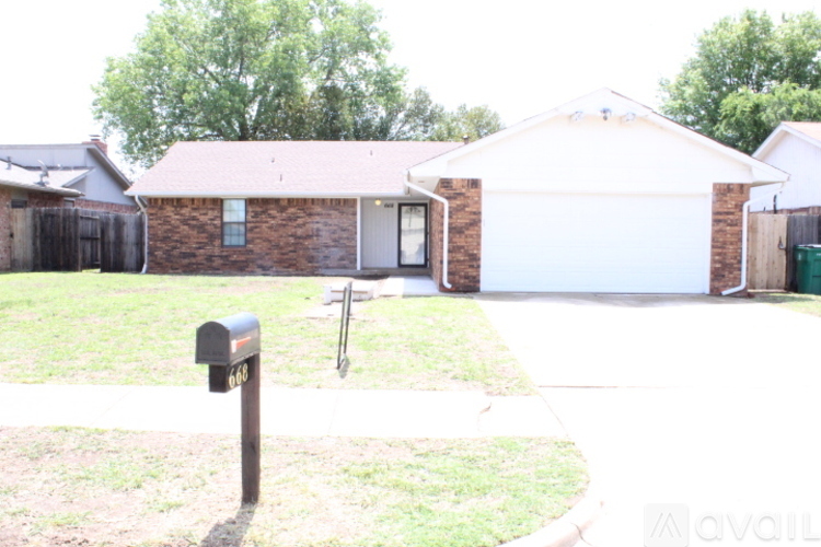 A brick house with a white garage door and a mailbox with the number 661 on it.