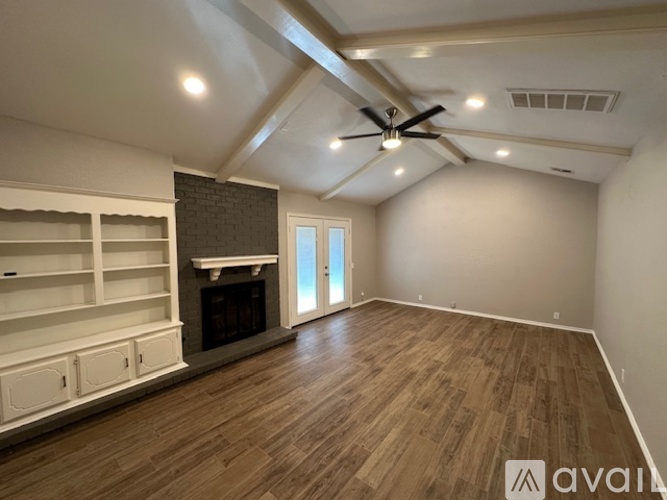 A spacious room with a fireplace and built-in shelves.