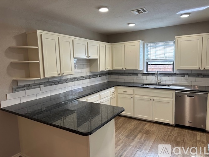 A kitchen with white cabinets and a black countertop.