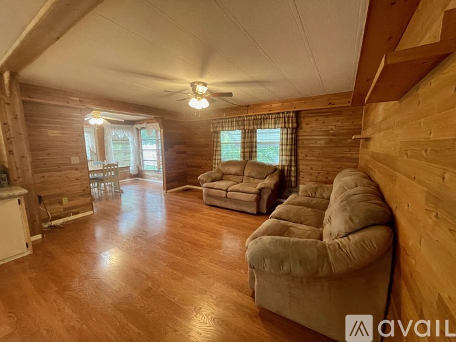 A living room with wooden walls and a light brown sofa.