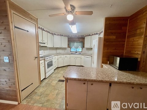 A kitchen with wooden cabinets and a ceiling fan.