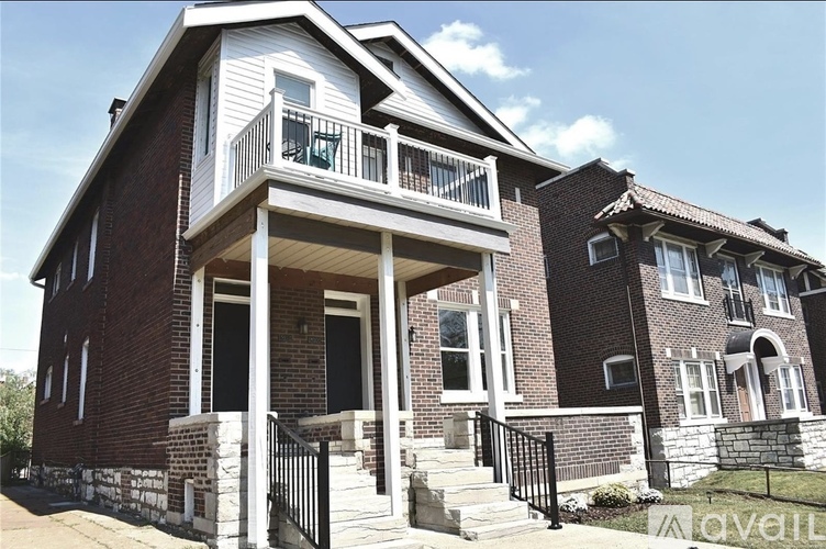 A two-story brick house with a balcony on the first floor.
