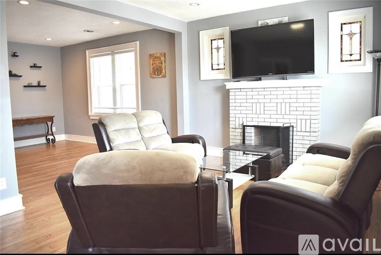 Two leather chairs with cushions are in front of a fireplace in a living room.