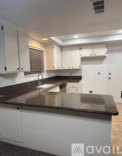 A kitchen with white cabinets and a granite countertop.