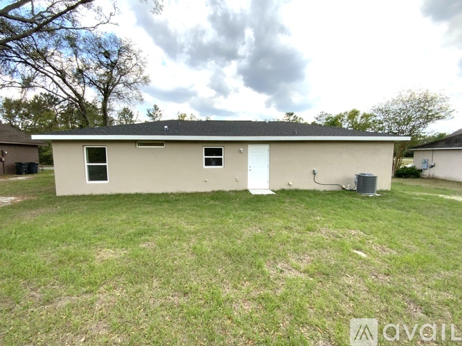 A small house with a white door and windows is surrounded by a grassy area.