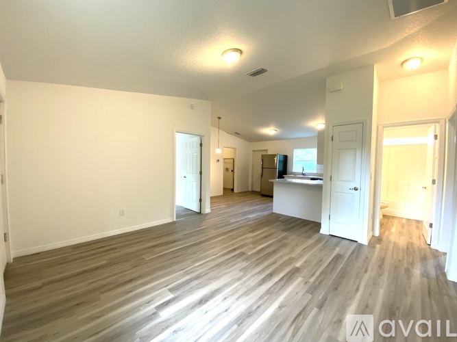 A spacious room with wooden flooring and white walls.