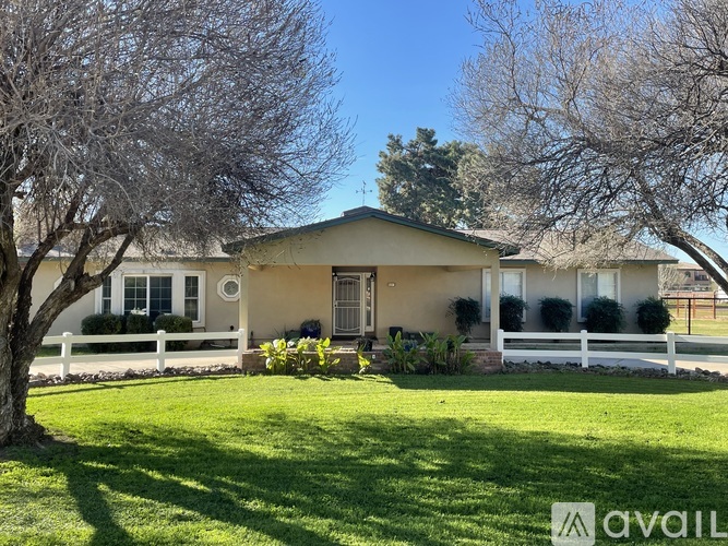 A house with a white fence and green lawn in front.