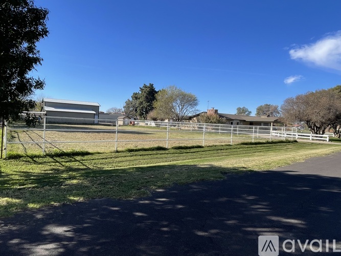 A fenced area with a building in the background and a clear blue sky.