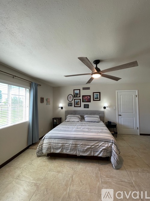 A bedroom with a bed, a ceiling fan, and pictures on the wall.