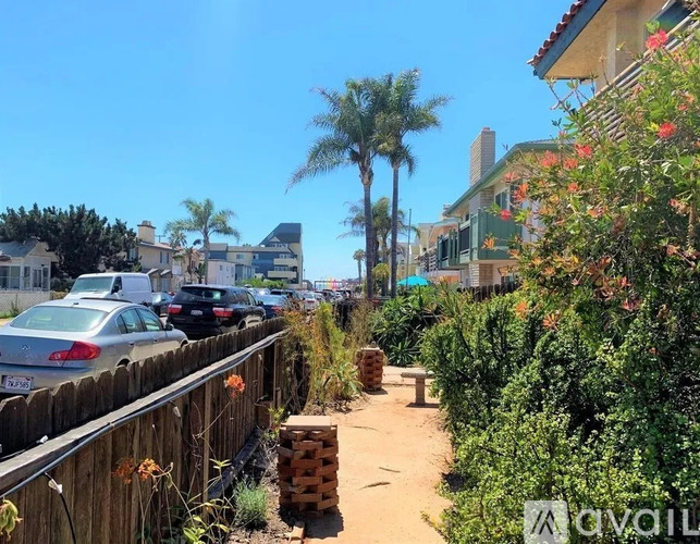 A sunny day in a residential area with cars parked along the street and houses with green shutters.