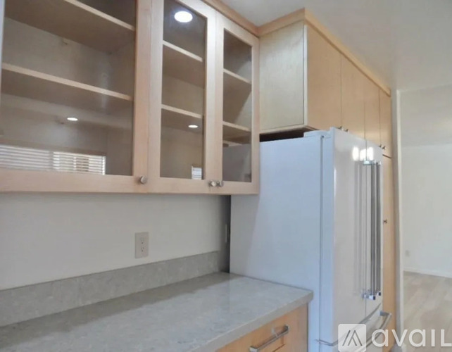 A kitchen with a white refrigerator and wooden cabinets.