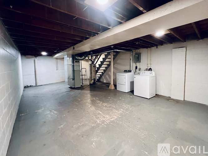 A spacious basement with a staircase and a couple of white appliances.