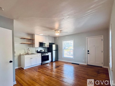 A kitchen with white cabinets and a wooden floor.