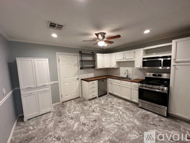 A kitchen with a marble floor and white cabinets.