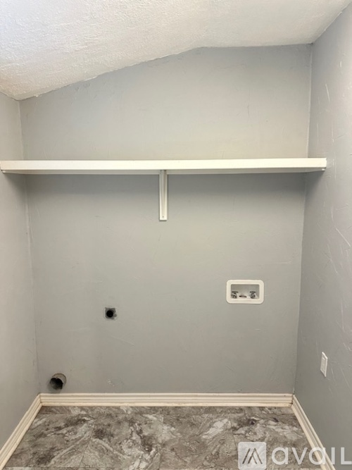 A room with a white shelf and a grey wall.