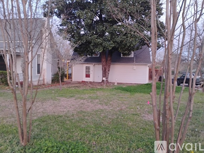 A house with a red door is surrounded by trees and grass.