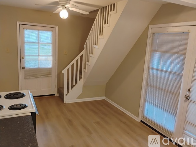 A kitchen with a stove top oven and a staircase in the background.