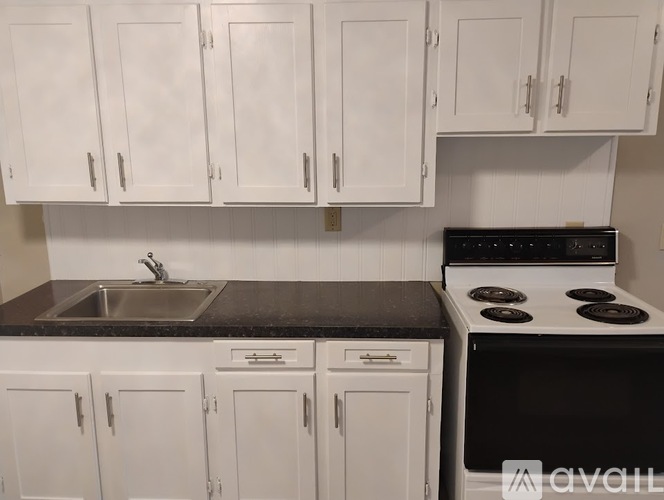 A kitchen with white cabinets and a black stove top oven.