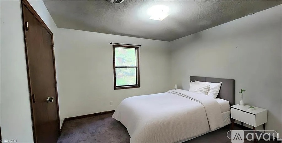 A bedroom with a bed, nightstand, and window.