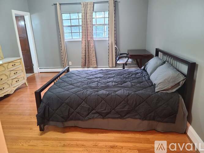 A bedroom with a large bed and a wooden floor.