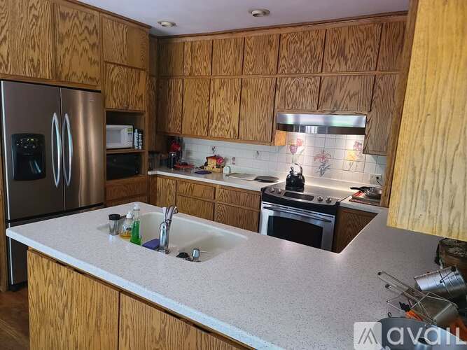 A kitchen with wooden cabinets and a stainless steel refrigerator.