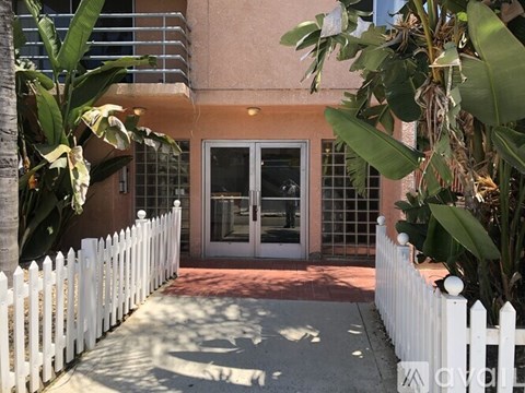 A white picket fence leads to a glass door entrance.