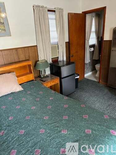 A bedroom with a bed, a dresser, and a window.