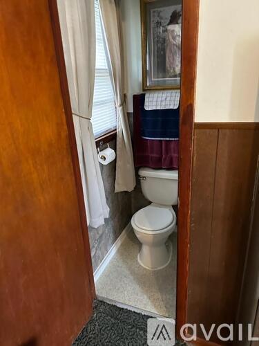 A white toilet is in a small bathroom with a wooden door.