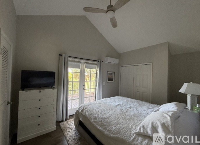 A bedroom with a bed, dresser, and a ceiling fan.
