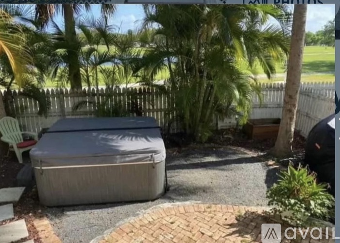 A hot tub is in a backyard surrounded by a fence and trees.