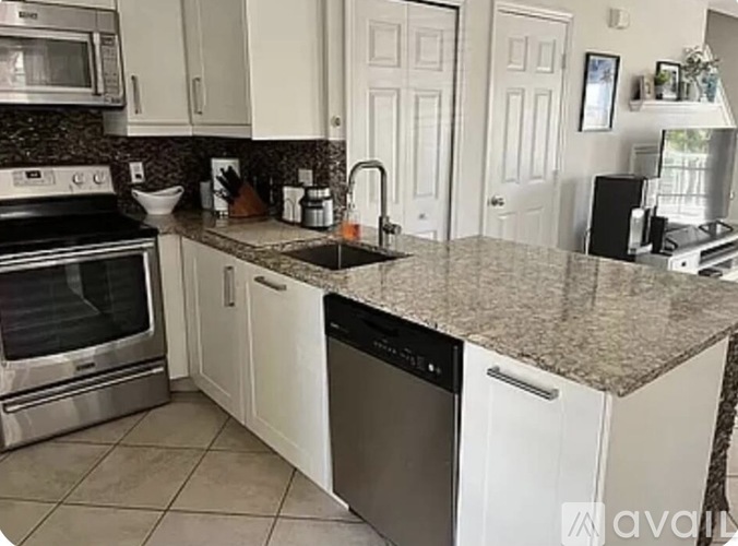 A kitchen with white cabinets and a granite countertop.