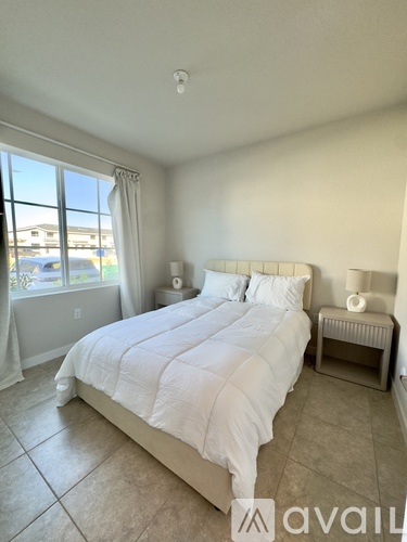 A bedroom with a large bed and a window overlooking a parking lot.