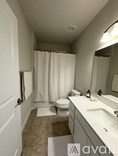 A bathroom with a toilet, sink, and shower curtain.