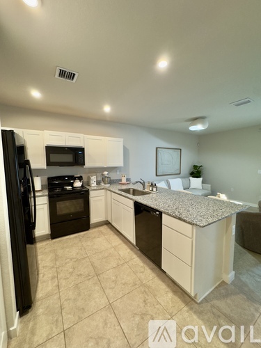 A kitchen with white cabinets and a black refrigerator.
