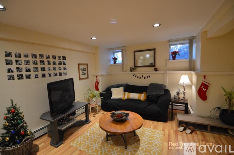 A living room with a black couch, a coffee table, and a television.