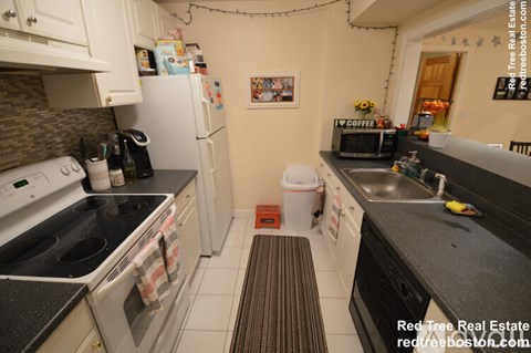 A kitchen with white cabinets and black countertops.