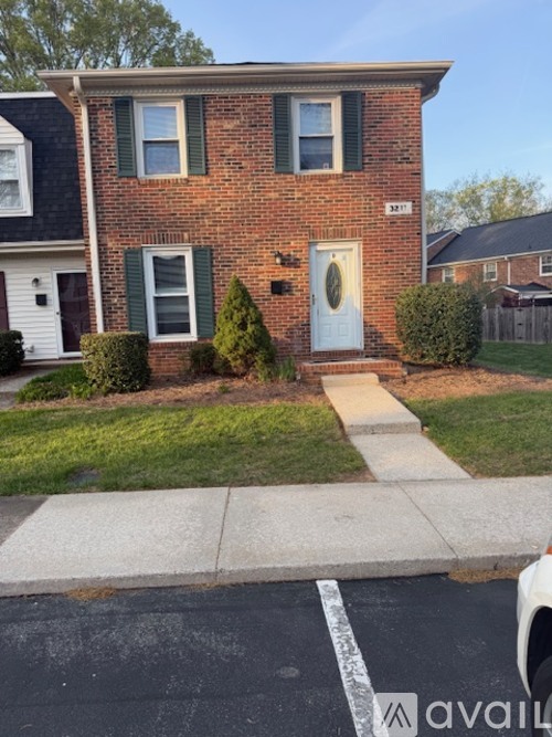 A brick house with a white door and green shutters.