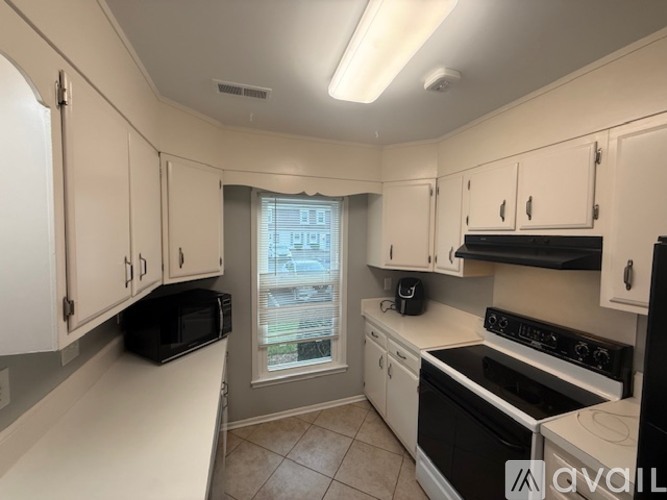 A kitchen with white cabinets and black appliances.